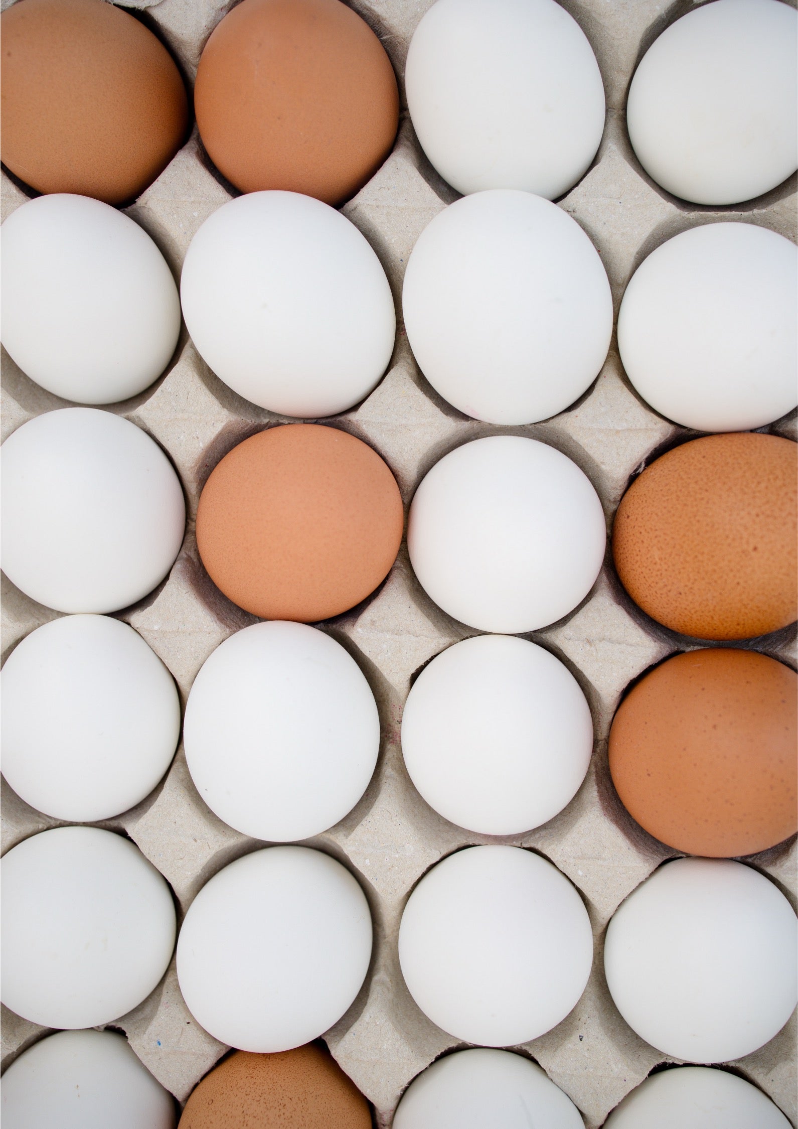A top-down view of brown and white eggs arranged in a cardboard egg carton.