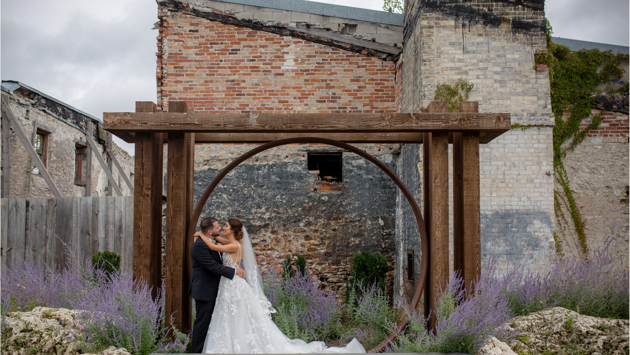 Bride and groom embracing under a wooden arch surrounded by lavender bushes